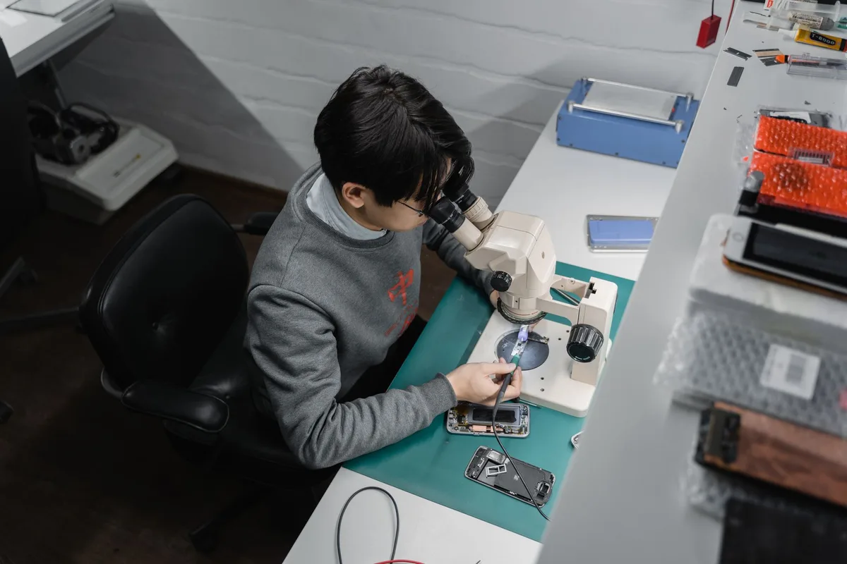 Teknisyen mikroskop altında iPhone TrueDepth kamera modülünü onarıyor