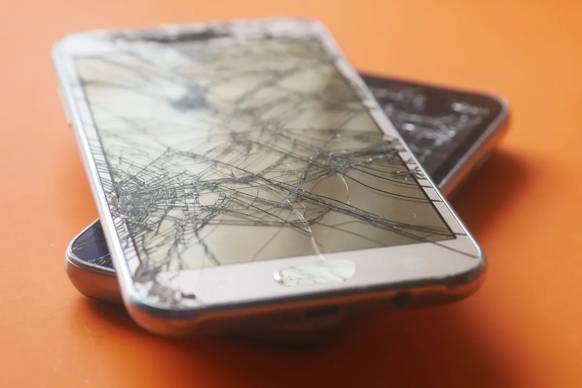 Teknisyen telefonun kırık arka camını ısıtma ve sökme işlemiyle değiştiriyor